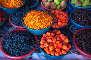 Assortment of different healthy wild berries in the baskets: sea buckthorn, physalis, black berberis (barberry) at the Osh Bazaar in Bishkek, Kyrgyzstan