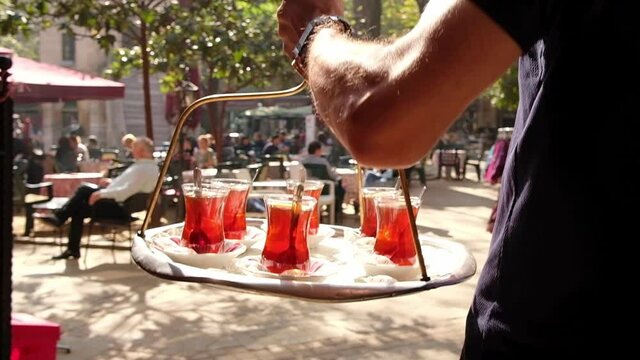 Waiter delivering traditional Turkish tea on a tray
