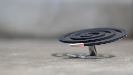 Purple mosquito repellent coil on cement floor background close-up.