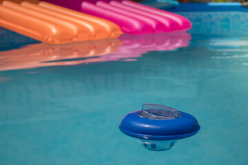 Piscina desmontable llena de agua con colchonetas y un dosificador de cloro