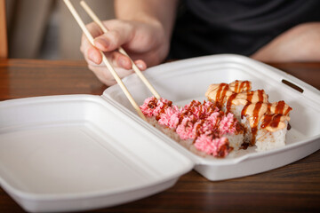 Container delivery sushi and hand with chopsticks. Fast food concept