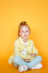 Beautiful portrat of young little girl in yellow studio and yellow bright clothes. Cute blonde child with plain healthy skin. Studio fashion model portrait
