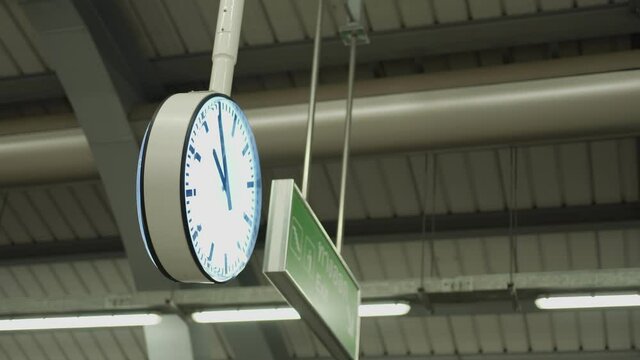Public train station clock, appointment at the station, time rush hour period, working hours weekday business running, big clock hanging down from train platform ceiling, evening night time