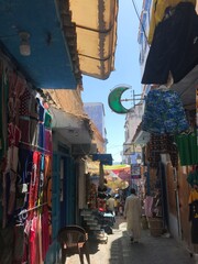 Obraz premium Chefchaouen, Morocco - July 29, 2019: A man walks past the handicraft stalls of the blue-painted alleys of the Medina.
