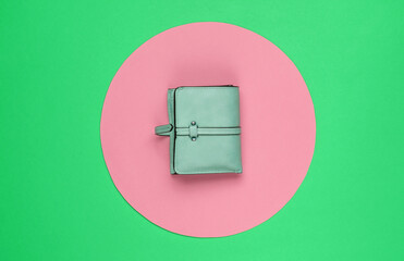 Stylish women's red leather wallet on green background with pink pastel circle. Creative...