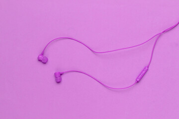 Wired earphones on purple background close-up. Music lover