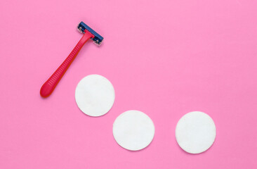 Beauty still life, minimalism. Plastic epilator razor with cotton circles on pink background. Women's accessories for beauty care. Top view