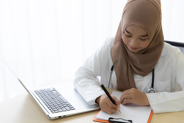 Young beautiful Asian woman Muslim doctor taking note and working at hospital, Medicine and health...