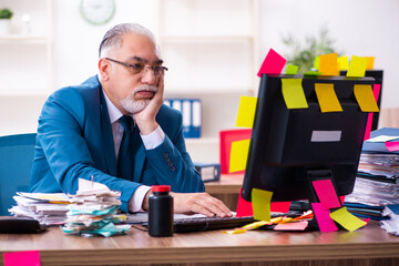 Old employee working in the office in conflicting priorities