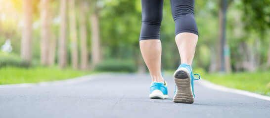 Young adult female in sport shoes running in the park outdoor, woman jogging and walking on the road at morning, leg muscles of Athlete. Exercise, wellness, healthy lifestyle and workout concepts