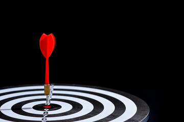 Red dart arrow hitting in the target center is Dart board on Black background