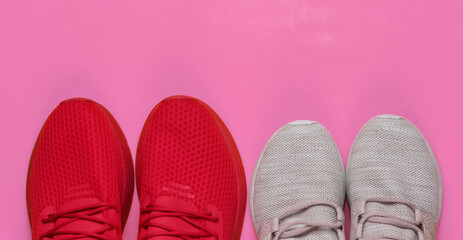 Two pairs of women's and men's sports shoes for running on pink background. Concept of couple doing sports.