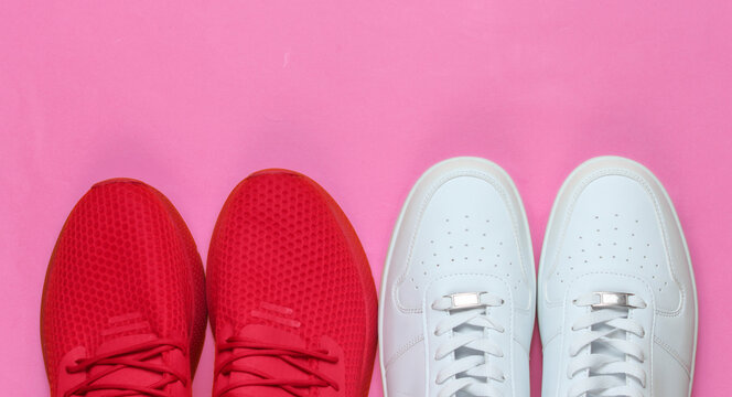 Two pairs of sneakers on pink background. White and red shoes. Top view