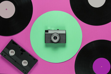 Retro vinyl record video cassette, film camera on a pink color background with a green circle. Top view