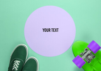 Fototapeta premium Cruiser board and sneakers on green background with a pink pastel circle in the middle for copy space. Youth hipster concept. Summer fun. Top view