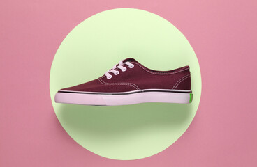Sneaker in the middle of pink background with yellow pastel circle. Youth hipster concept. Summer fun. Top view