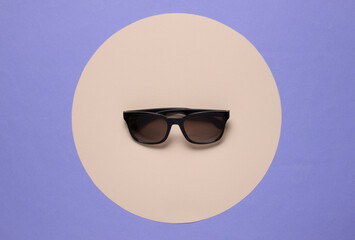 Sunglasses on purple background with yellow pastel circle. Top view