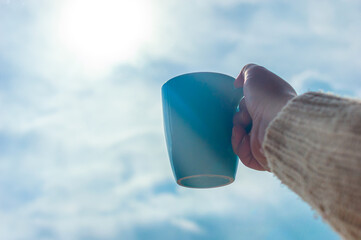 Woman's hand holding a mug, direction to heaven