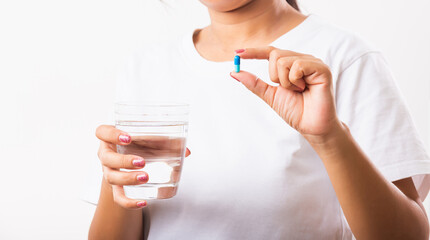 Closeup young Asian woman hold pill drugs in hand ready take medicines with a glass of water, studio shot isolated on white background, Healthcare and medical pharmacy concept