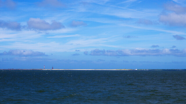 Panorama von Wangeroge vom Meer aus mit Horizontlinie und Wolken am Himmel