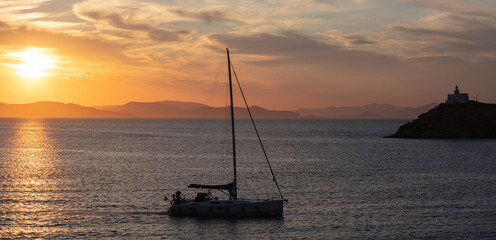 Naklejka na ściany i meble Mediterranean sea. Beautiful sunset and a lighthouse at Kea island, Greece.