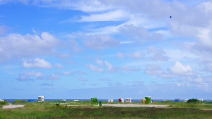 Panorama an der Nordsee von Dünen mit Strandkörben und Wolken am blauen Himmel