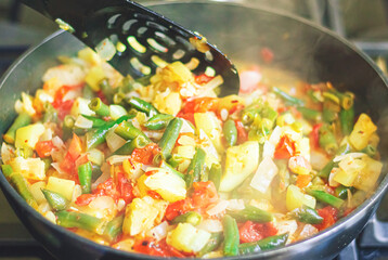 Cooking stewed vegetables in a deep pan, vegetarian food. Stew of zucchini, tomatoes, onions, paprika and string beans.Close-up.