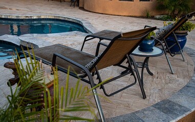 A travertine tile pool deck with plants and lounge chairs in the Arizona southwest .
