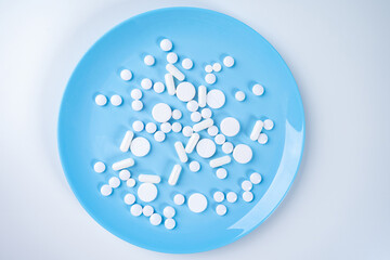 Pills on a blue plate. Taking medication while eating. Pharmacology. The combination of medication with food. Prescribing medications for treatment and prevention.