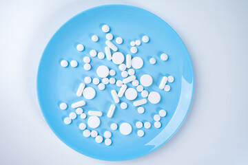 Pills on a blue plate. Taking medication while eating. Pharmacology. The combination of medication with food. Prescribing medications for treatment and prevention.