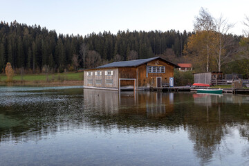 Fototapeta premium Erlaufsee - a mountain lake at the foot of the Alps in Lower Austria. Wooden yard standing in the water. Green boat parked on the right.