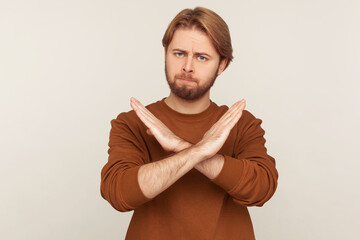 No access, prohibited way! Portrait of bearded man crossing hands, showing stop gesture with x...