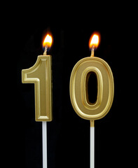 Burning golden birthday candles isolated on black background, number 10
