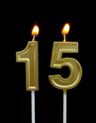 Burning golden birthday candles on black background, number 15	