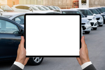 Hands with digital tablet on a background of rows of cars. Car sales.	