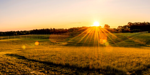 Beautiful sunset over a farmland, with sunburst, sunstars © Yan
