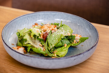 caesar salad with shrimp, pine nuts, parmesan cheese in a deep plate on a table in a restaurant. healthy eating. organic food. detox