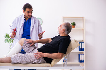 Old injured man visiting young male doctor traumatologist