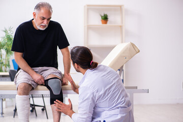 Old injured man visiting young male doctor traumatologist