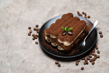 Classic tiramisu dessert on ceramic plate on concrete background
