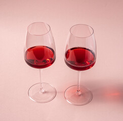 Glasses of red wine on pink background, top view.