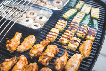 BBQ on weekend. Chicken wings, cheese and vegetables on gas grill. Outdoors.