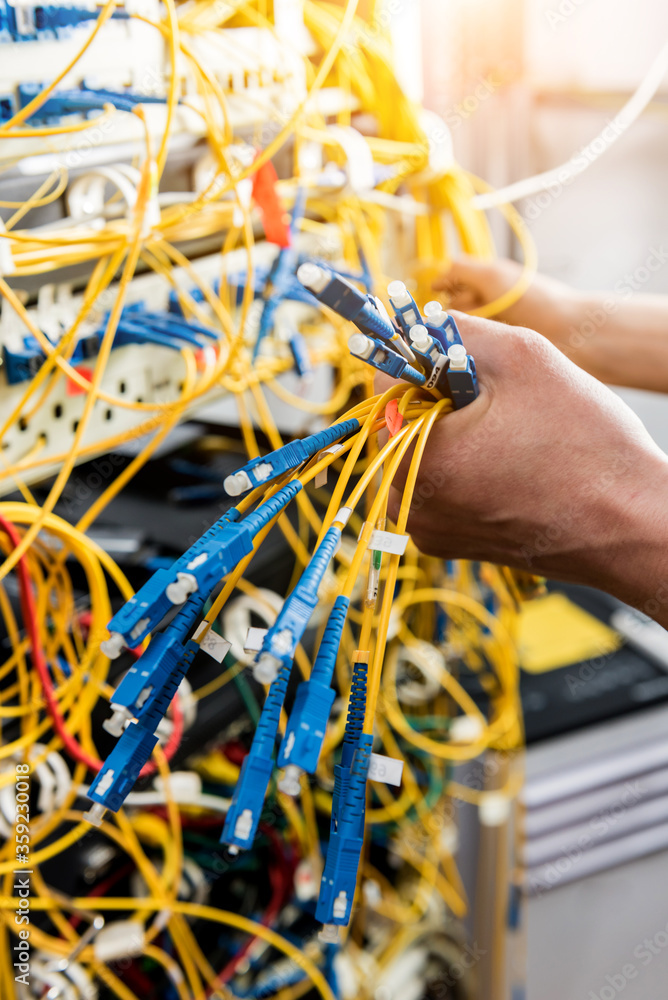 Wall mural network engineer working in server room. connecting network cables to switches