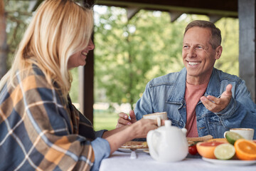 Merry loving spouses enjoying time together during breakfast outdoors