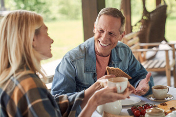 Happy mature couple enjoying hot drinks with toasts