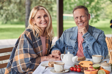 Cheerful mature couple during breakfast in veranda outdoors