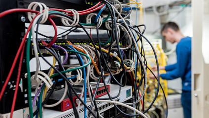 Network engineer working in server room. Connecting network cables to switches