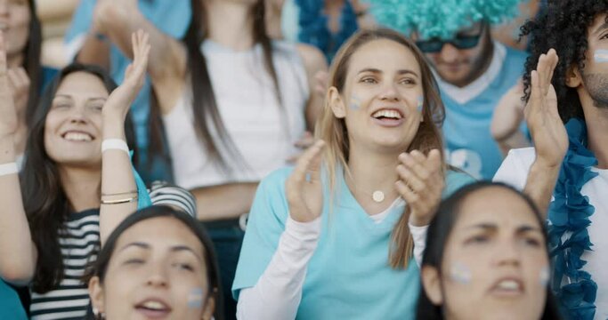 Excited sports fans at live game chanting and cheering for their team. Young people watching football match chanting to cheer argentinian national team.