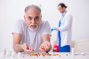 Young male doctor visiting old male patient at home