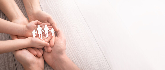 Family care concept. Hands with paper silhouette on table.